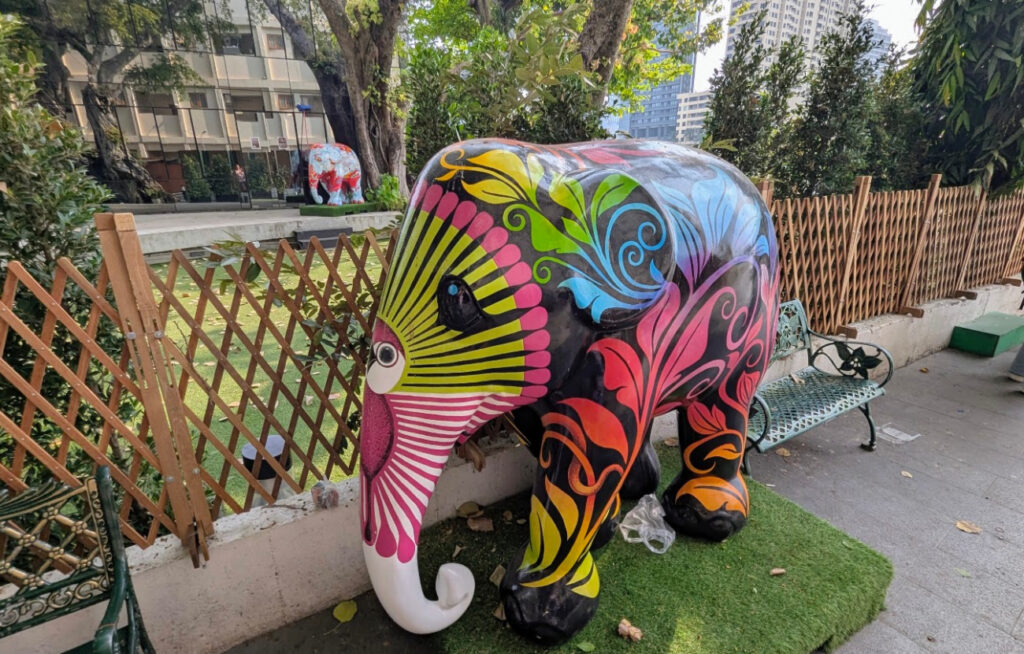 Verket heter Plant Paradise. Det viser en tett, tropisk jungel med blader i sterke farger som lilla, oransje og grønt mot en dyp, mørk bakgrunn. Dette symboliserer elefantens naturlige habitat og viktigheten av å bevare de thailandske regnskogene. 