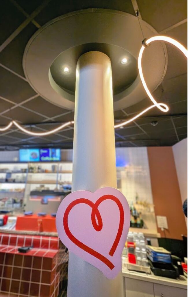 Interiørdetalj fra Scandic GO med et lekent hjertesymbol på en søyle og moderne belysning i bakgrunnen.