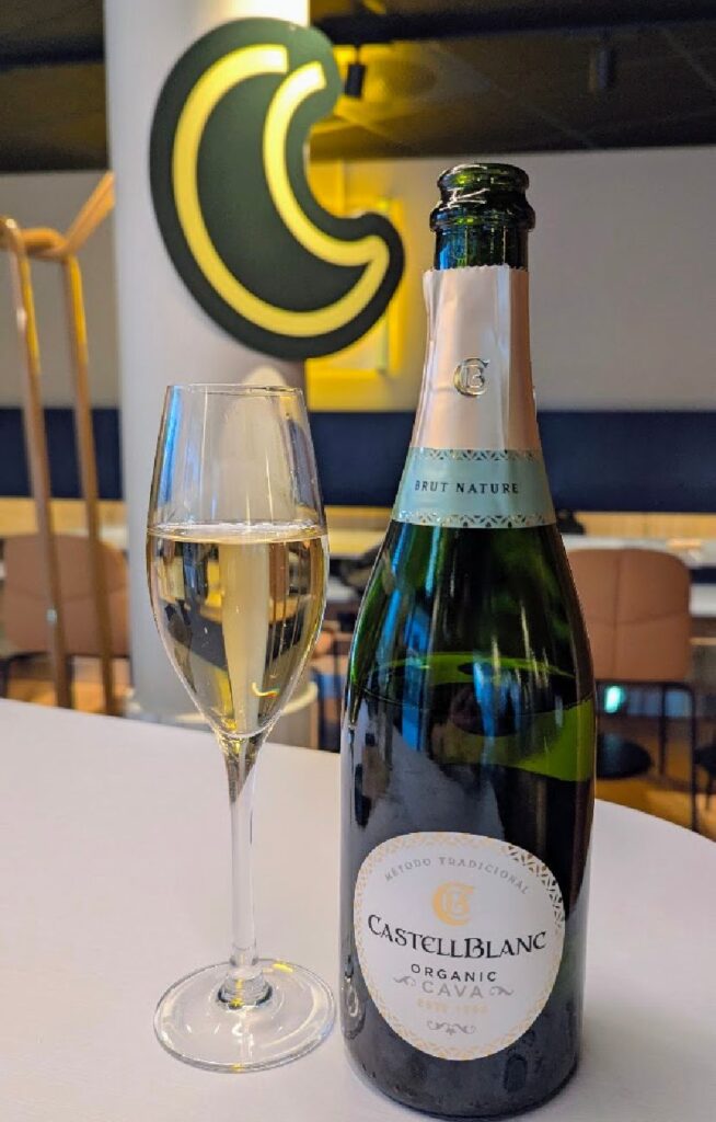 En flaske Castellblanc Organic Cava og et fylt glass på et hvitt bord under åpningen av Scandic GO.