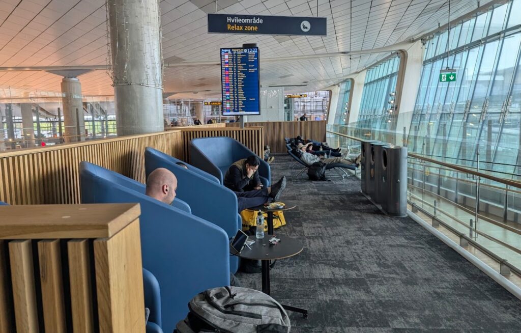 Rolig hvileområde og relax sone med blå skjermede stoler og liggestoler ved gate C på Oslo Lufthavn Gardermoen.